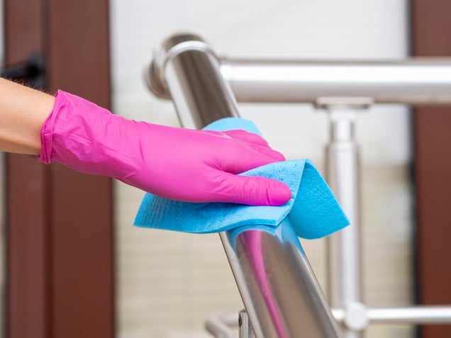 hand-rail-being-disinfected-by-person-with-cloth-surgical-glove